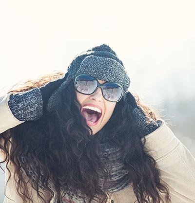 mujer pelo largo rizado con gorro de invierno y gafas de sol